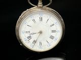 une montre de poche en argent avec des chiffres romains sur le cadran
