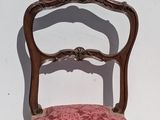 a pink chair with a wooden frame on a white wall