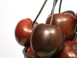 a metal bowl filled with cherries on top of a table