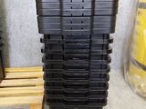 une pile de bacs en plastique noir posée sur une palette en bois