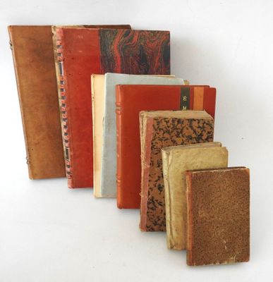 several old books are lined up in a row on a white surface