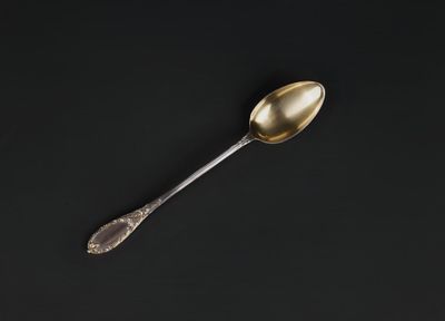 a silver spoon with a gold handle sitting on a black surface
