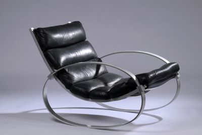a black leather chair with a metal frame on a grey background