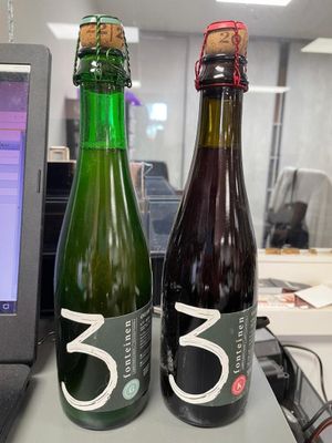 two bottles of beer sitting next to each other on a desk