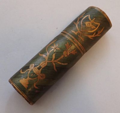 a green and gold case with a flower design on it