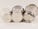 three silver salt shakers sitting next to each other on a white surface