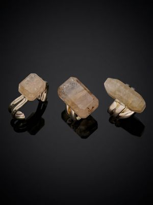 three gold rings with quartz stones on a black surface
