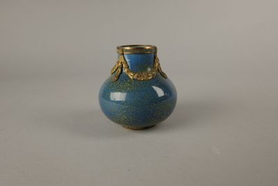 un petit vase bleu orné d'un motif doré
