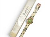 a close up of a watch with a box on a white surface