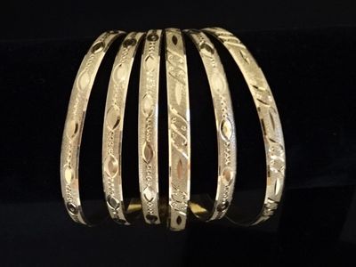 gros plan d'un bracelet en or sur une surface noire