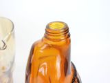 a brown glass bottle sitting on a table next to a glass cup