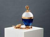 an image of a blue and white perfume bottle sitting on top of a white pedestal