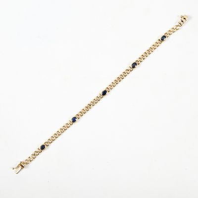 un bracelet en chaîne dorée orné de pierres noires sur fond blanc