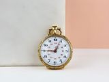 a small gold watch sitting on a white table