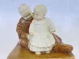 une figurine représentant un garçon et une fille assis sur un banc