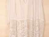 white lace dress hanging on a hanger on a wooden wall