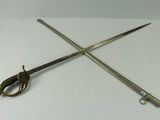 two swords on a white table with a pair of scissors