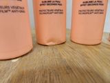three bottles of body lotion sitting on a wooden surface