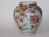un vase bleu et blanc orné de fleurs rouges