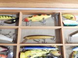 many different types of fishing lures in a wooden box
