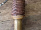 a small brass pipe on a wooden table with a chain