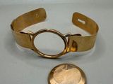 bracelet plaqué or, avec une pièce posée sur une table à côté