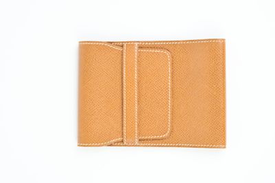 un gros plan d'un portefeuille en cuir beige sur fond blanc