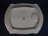 a white porcelain urinal with a white lid on a black table