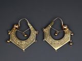 a pair of gold earrings with pearls on them on a black surface