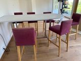 a white table with purple chairs in the middle of the room