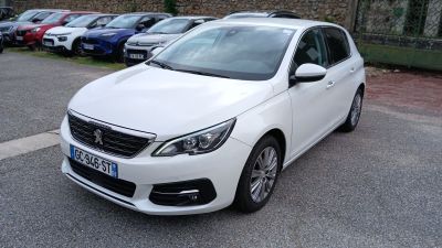La voiture blanche est garée sur le bord de la route, dans le parking.