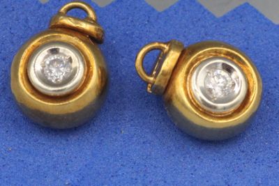 une paire de boucles d'oreilles en or et diamants sur fond bleu