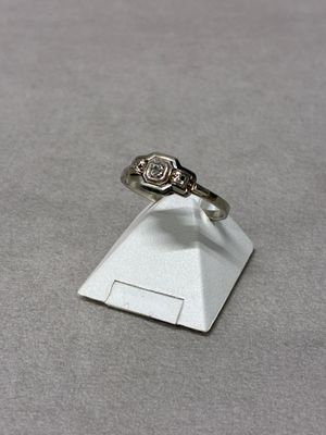 silver ring with a diamond on top of a small white pyramid