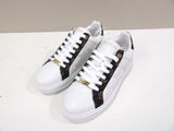 white sneakers with black and gold details on them on a white surface