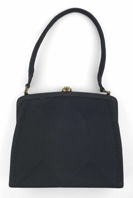 le petit sac à main noir est posé sur une surface blanche