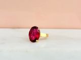 une photo en gros plan d'une bague en pierre rouge posée sur une surface en marbre