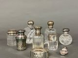 an assortment of silver and glass perfume bottles on a table