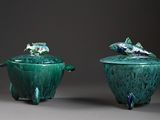 two green vases with fish on top of them sitting on a table