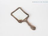 a small mirror with a wooden handle on a white surface