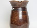 a brown vase that is sitting on a white surface