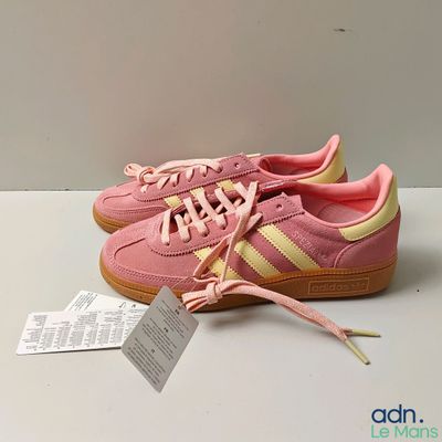 des baskets Adidas roses et jaunes posées sur une surface blanche, avec une étiquette de prix