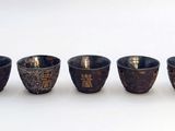 four small cups are lined up in a row on a white surface