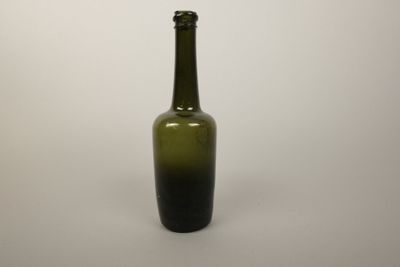 une bouteille en verre verte posée sur une surface blanche