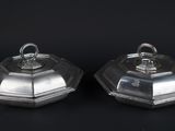 two silverplated dishes with lids on a black background