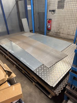une tôle d'acier dans un entrepôt, avec des cartons et des palettes en arrière-plan