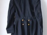 navy blue jacket with gold buttons on a hanger on a white wall
