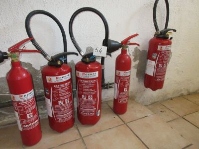 cinq extincteurs alignés contre un mur