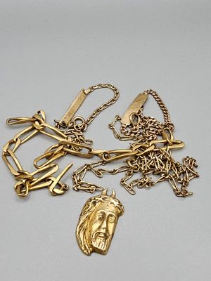 plusieurs colliers en or et un porte-clés en or posés sur une surface blanche