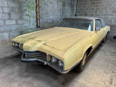 an old yellow car is parked in a garage with a brick wall