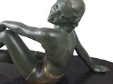 bronze statue of a woman sitting on a black surface